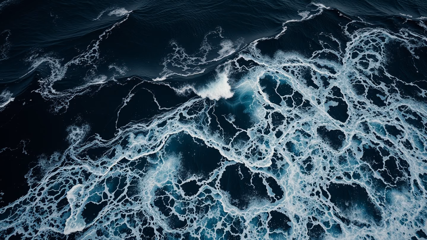 Epic panoramic view of a turbulent, dark ocean at high altitude, with crashing waves forming intricate patterns of white foam against black water.