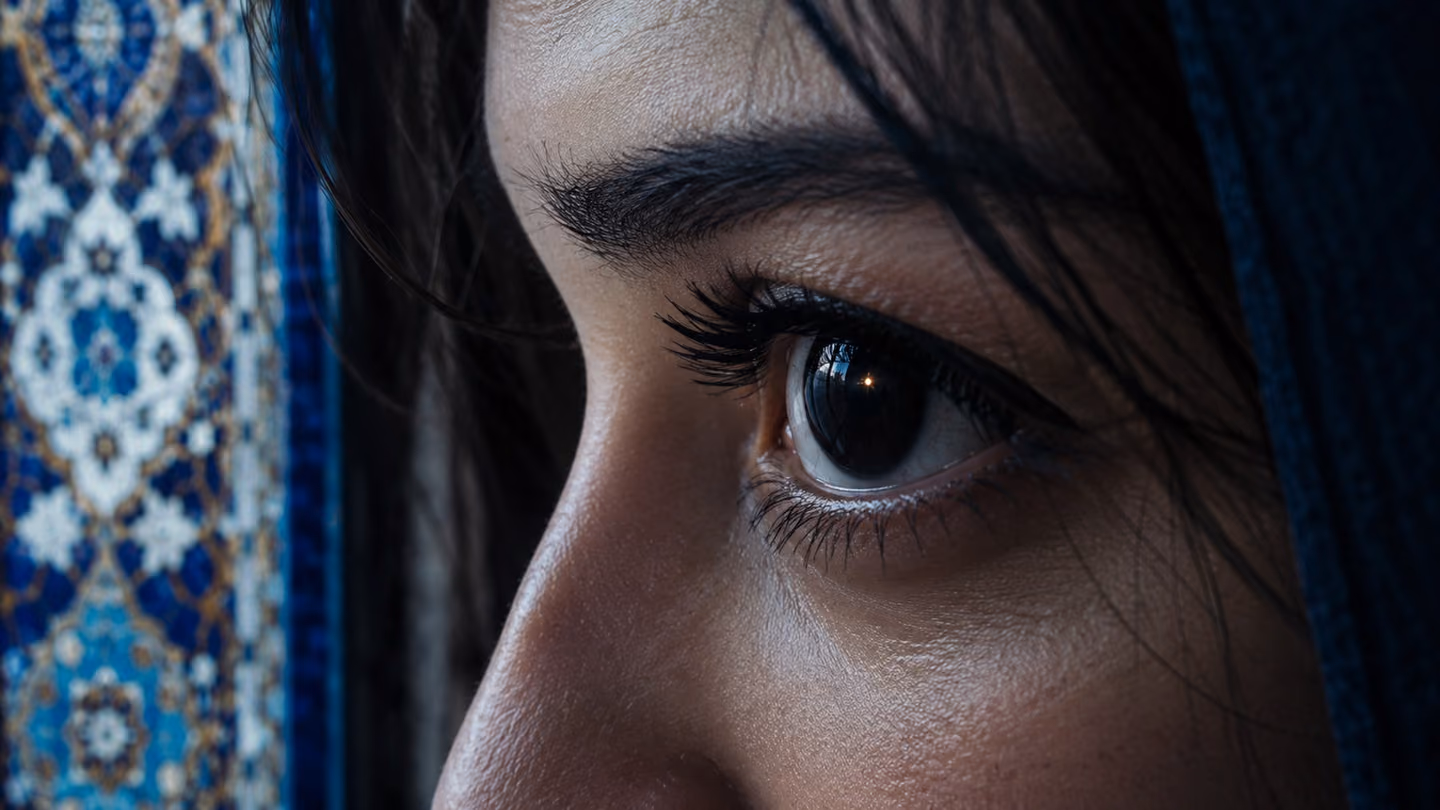 Extreme close-up, three-quarter angle, of a woman's dark Persian eye — deep black iris, long lashes, a single reflected point of candlelight shimmering in the pupil like a star — her gaze steady and fathomless, the su…