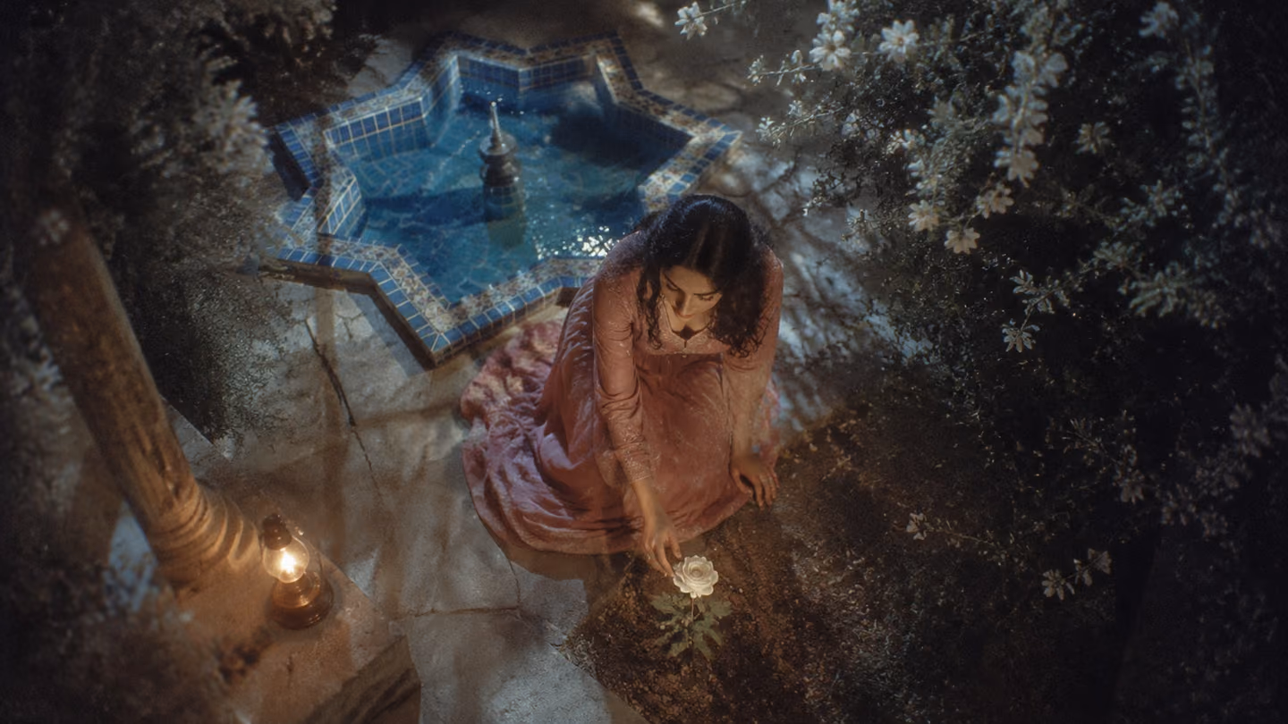 The same graceful 30-year-old Iranian woman kneels in a moonlit Persian garden courtyard, her palm pressed gently to the earth, a single white rose blooming vibrantly at her fingertips, silver moonlight filtering thro…
